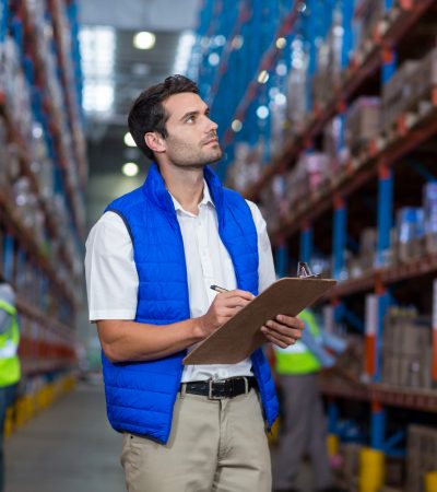 Warehouse worker writing on clipboard in warehouse